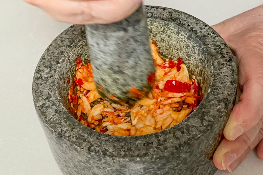 Hvitløk støtes i morter med chili